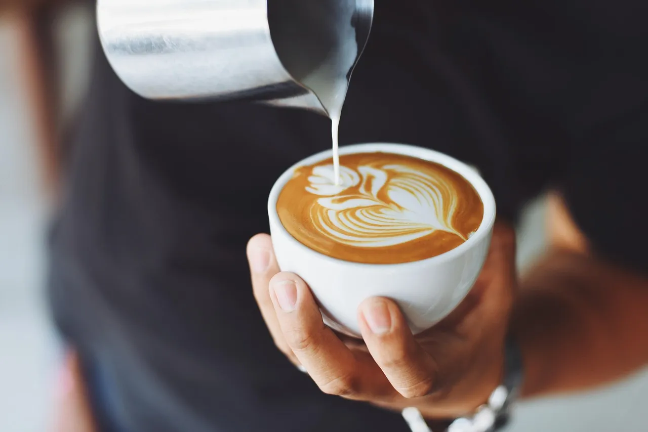 Barista menuang susu ke espresso membentuk latte art