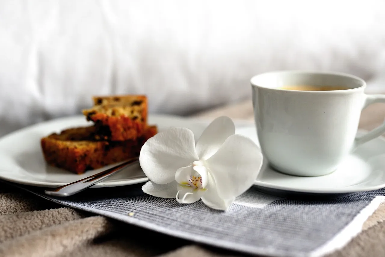 Secangkir kopi dan kue di atas meja dengan bunga anggrek