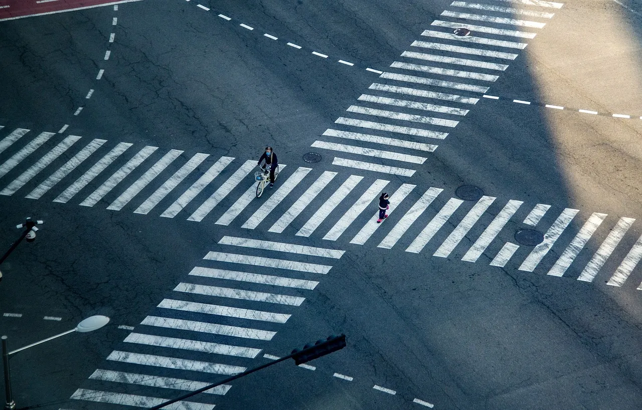 Pesepeda melintasi zebra cross di persimpangan kota, dilihat dari atas